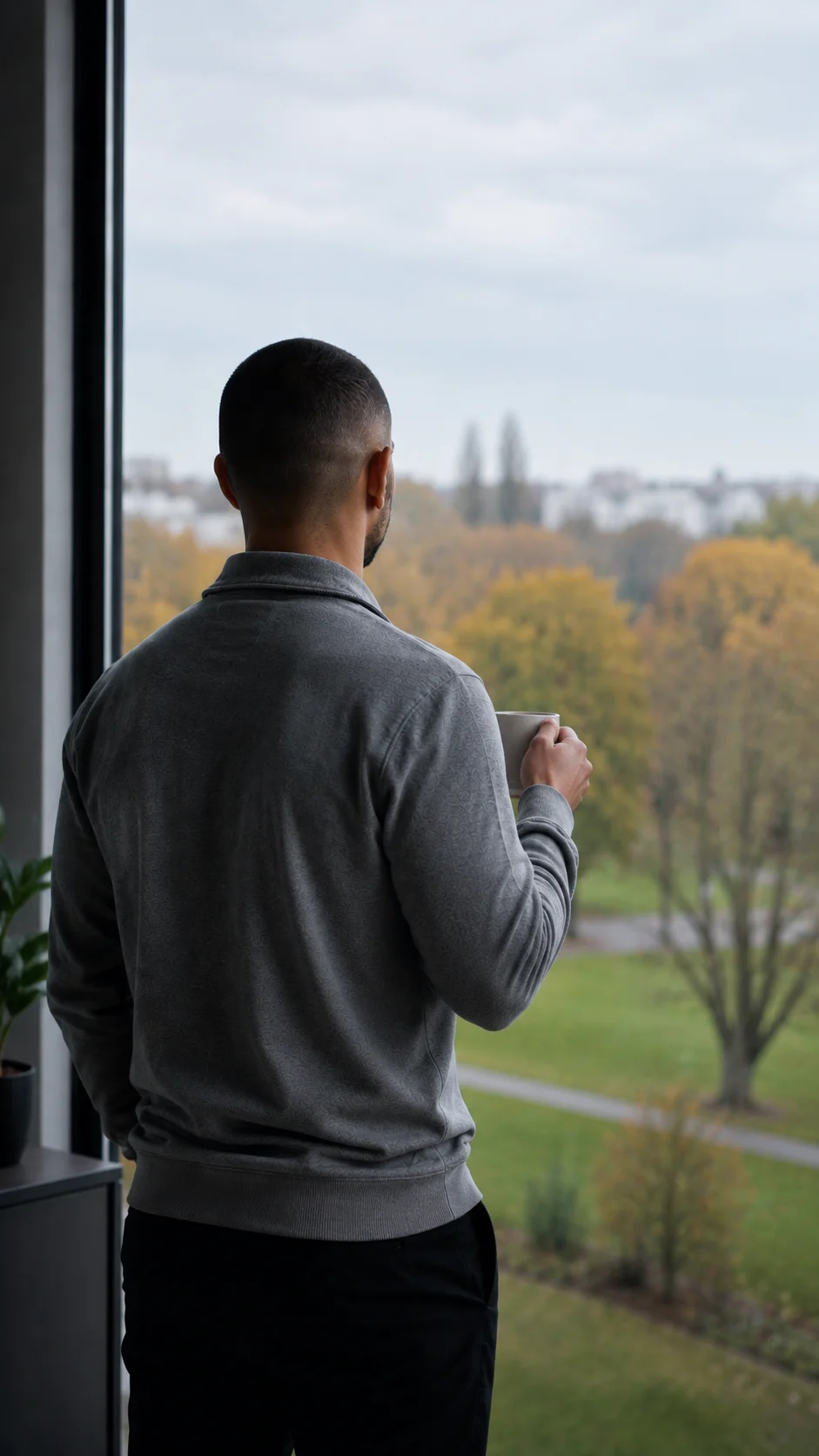 Nachdenklicher Mann blickt aus Fenster auf Herbstlandschaft – Reflexion und innere Klarheit im Life Coaching